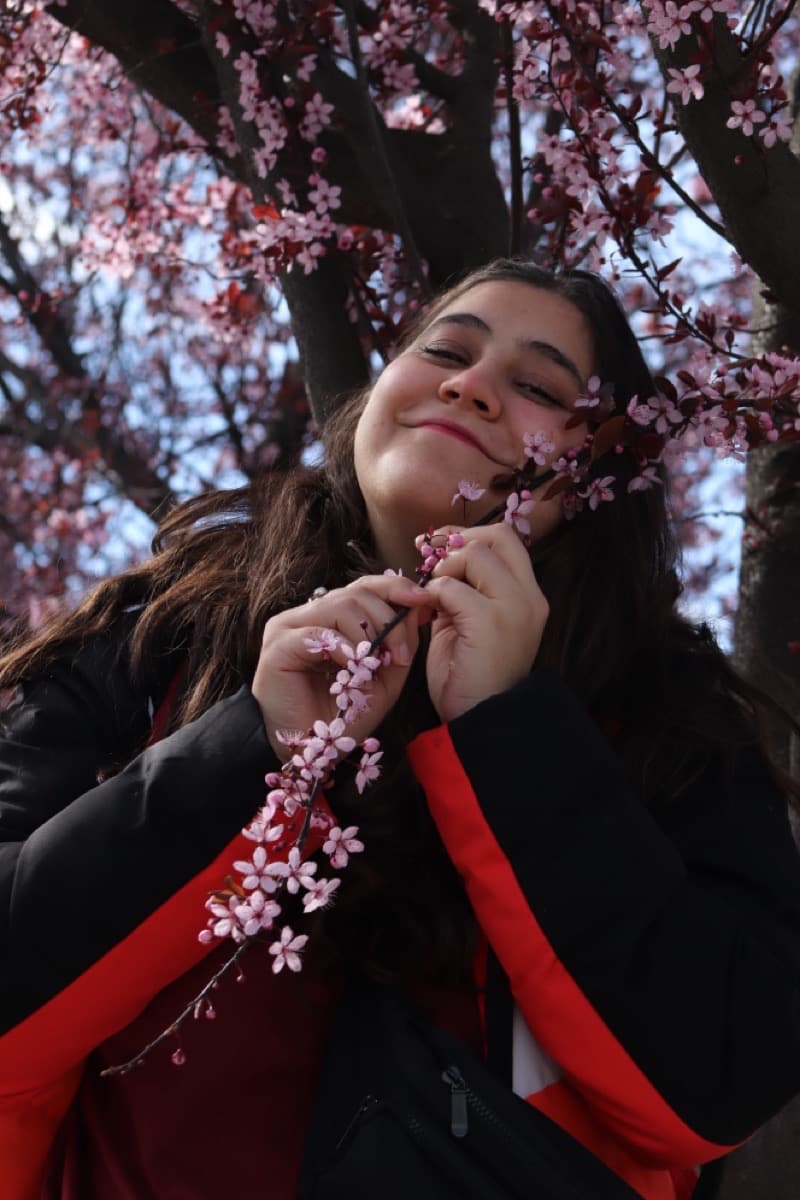 Lara Mateo holding a branch of pink cherry blossoms